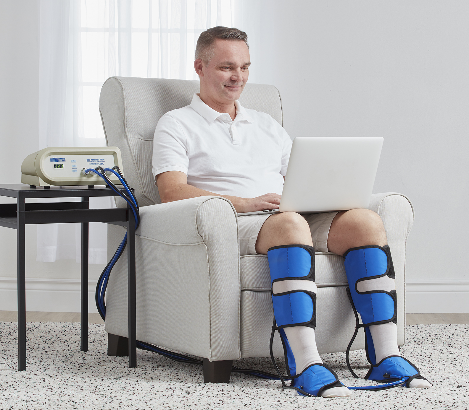 Patient at home using a medical-grade arterial pump to improve lower leg circulation. Patient at home using a medical-grade arterial pump to improve lower leg circulation.