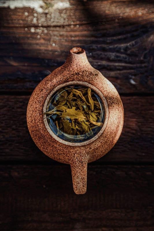view from above of a rustic tea pot with tea leaves 