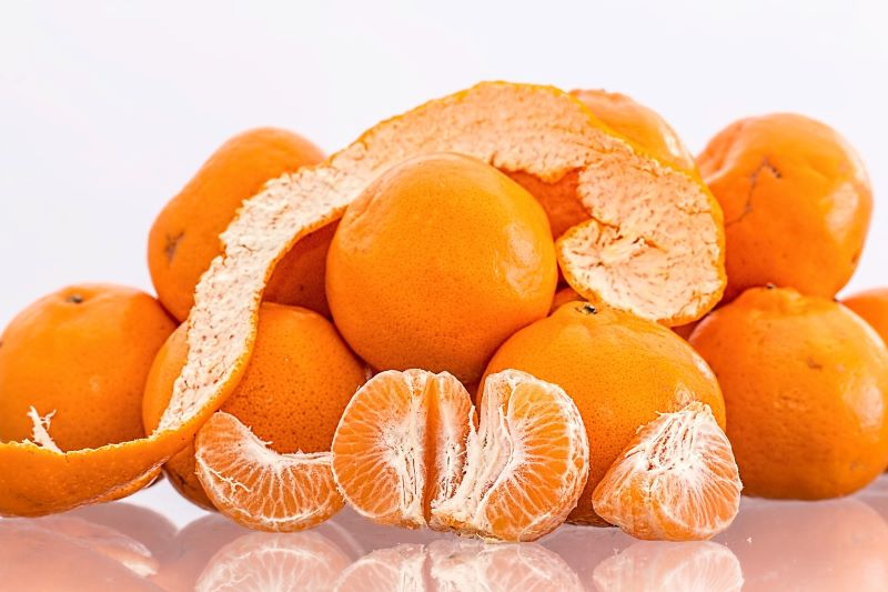 a pile of unpeeled and peeled mandarins against a white background a pile of unpeeled and peeled mandarins against a white background