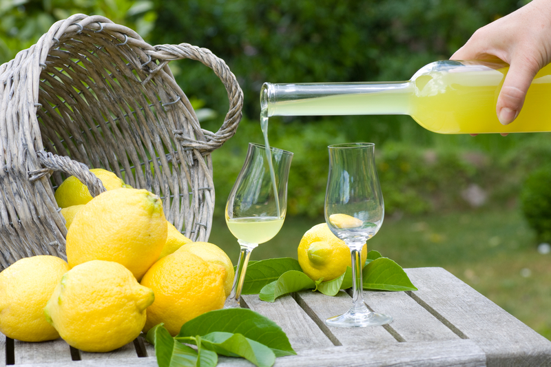 a hand holding a bottle and pouring limoncello into a glass a hand holding a bottle and pouring limoncello into a glass
