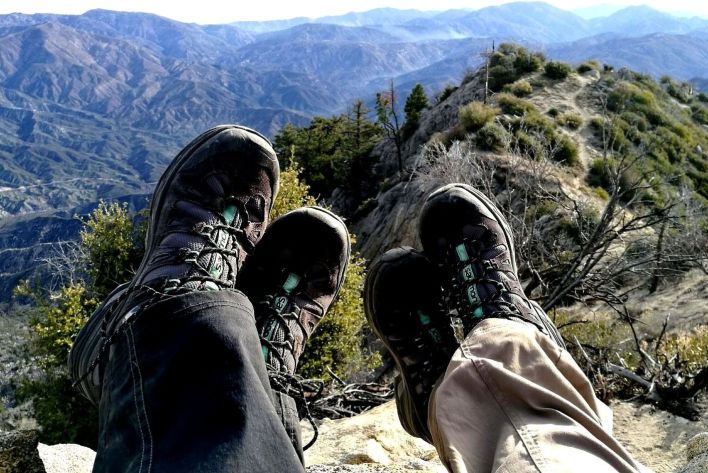 Two hikers taking a rest with their feet overlooking a beautiful scenery