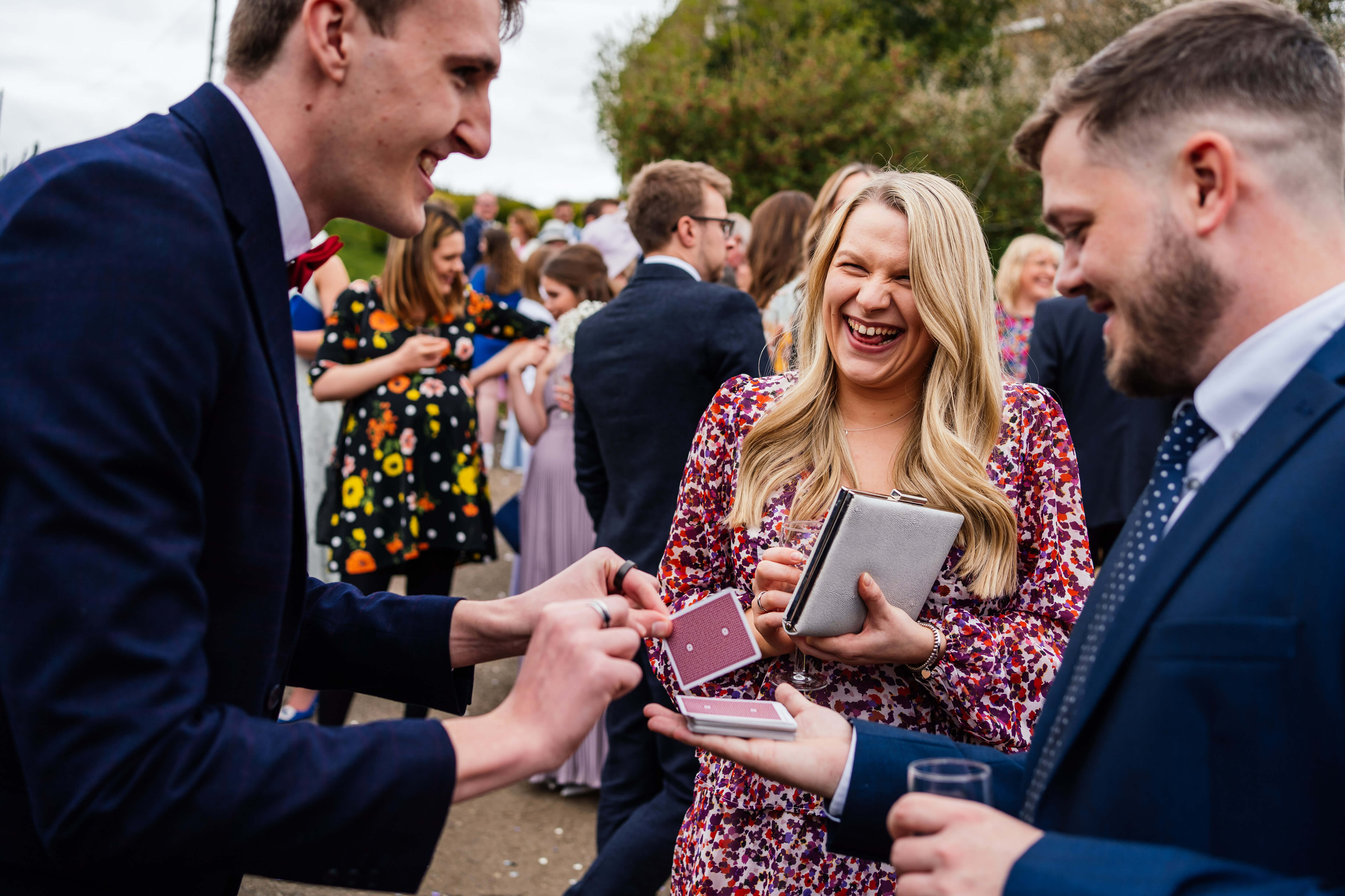Guests laughing during close-up magic at an outdoor event