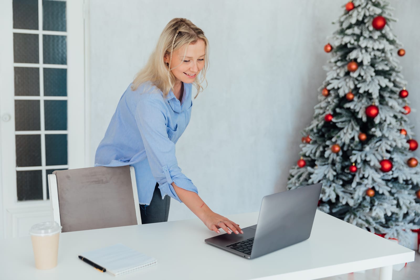 Lächelnde Frau vor dem Weihnachtsbaum am Laptop Lächelnde Frau vor dem Weihnachtsbaum am Laptop