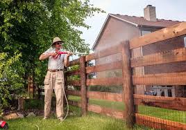 a man spraying the wooden fence