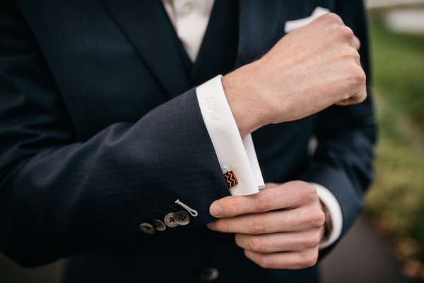 Man adjusting his tailored suit jacket, looking thoughtful and professional