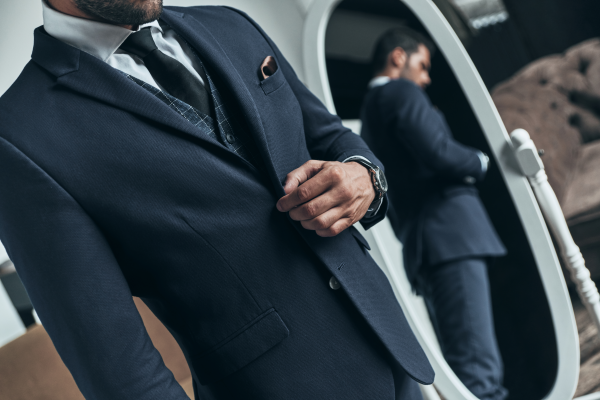 Confident in his style. Close up of young man in full suit adjusting jacket while standing indoors