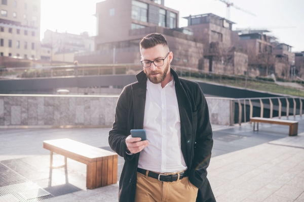 Young bearded man outdoor using smartphone searching online