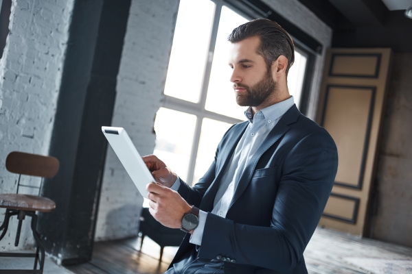 Working hard Confident and young businessman in stylish suit is using his tablet