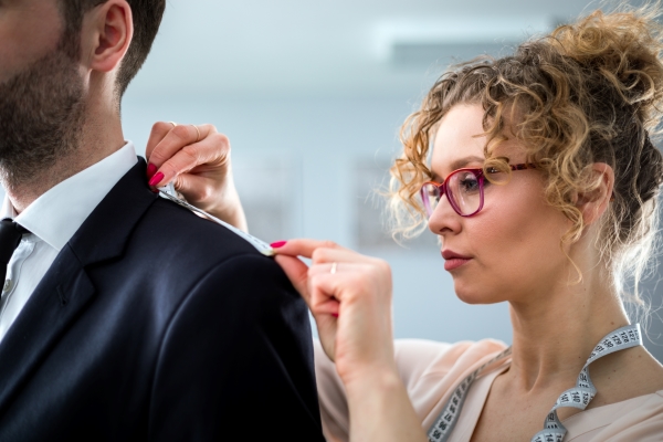 Tailor using tape to measuring client for sewing suit at atelier