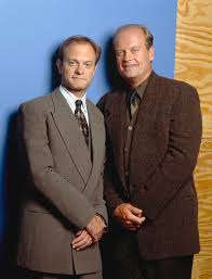 Niles and Frasier stook against a wall smiling from Frasier