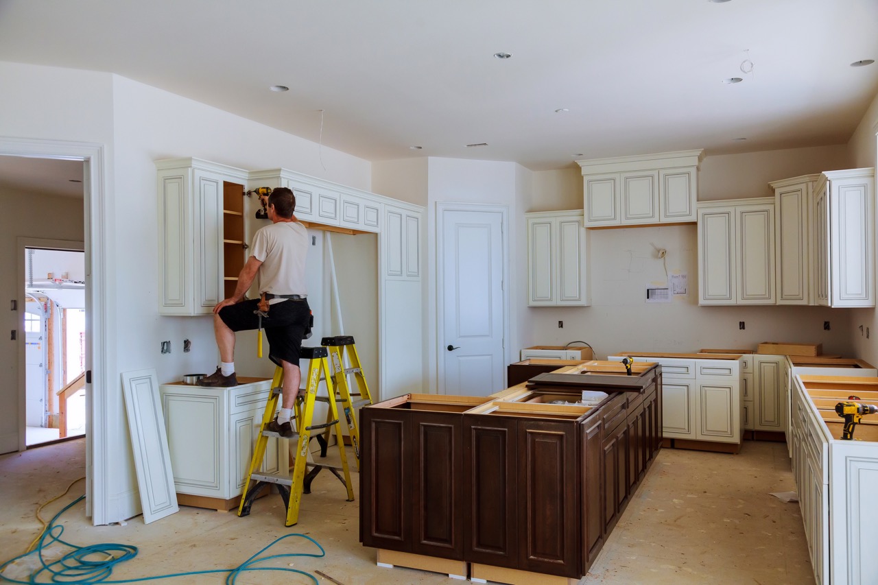 a man installing kitchen cabinets 