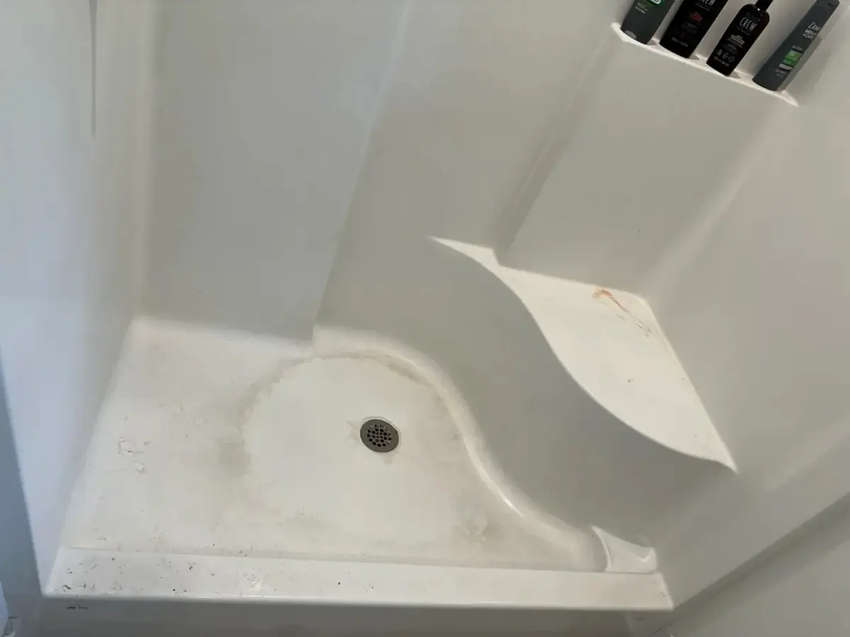 alt="Before photo of a white shower stall in a Maryland home with significant grime and mildew buildup on the floor and walls."