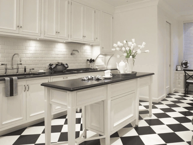 a kitchen remodeling features white cabinets, a black countertop island, and a striking black-and-white checkered floor.