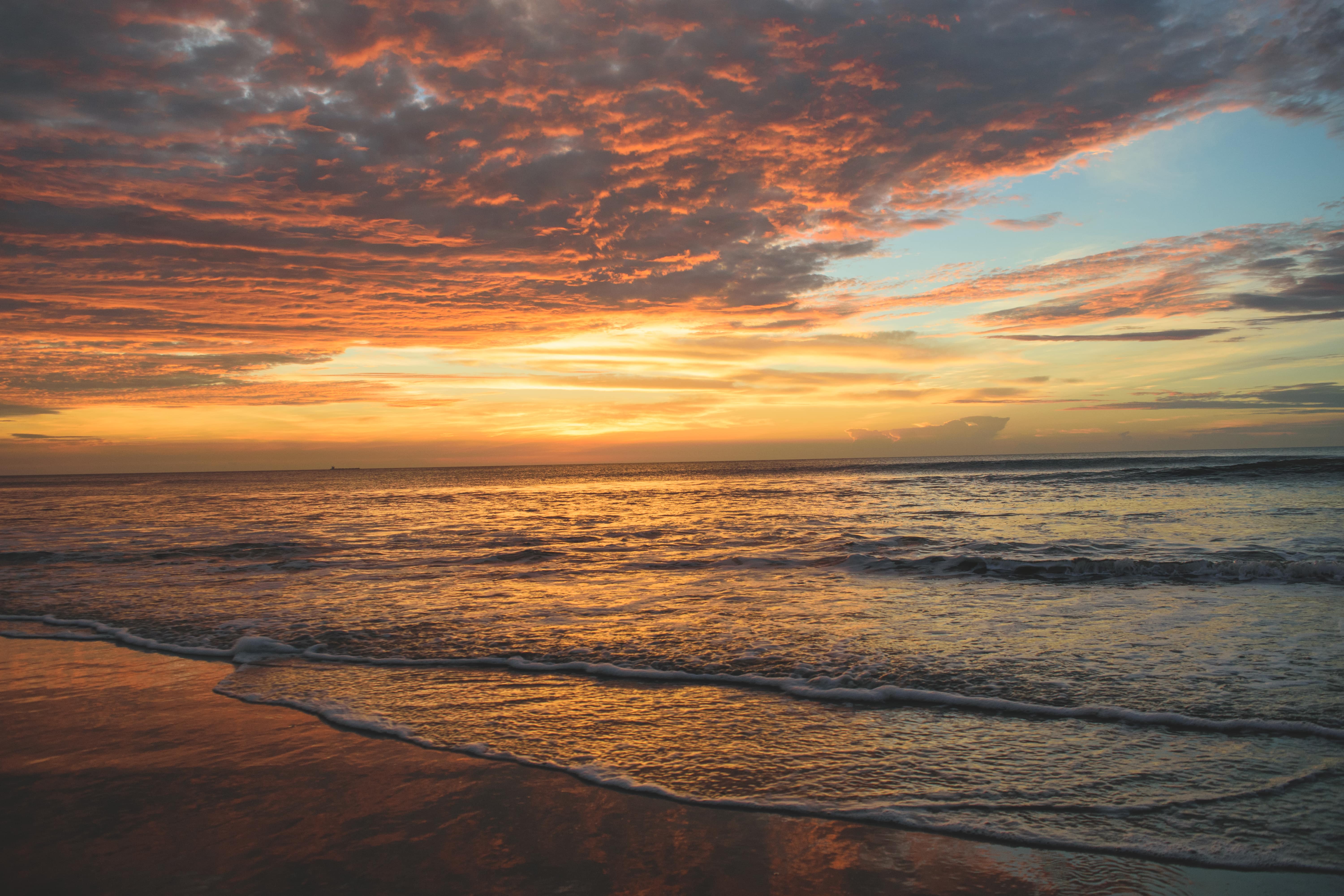 Sandy beach with orange sunset and small tide on the beach