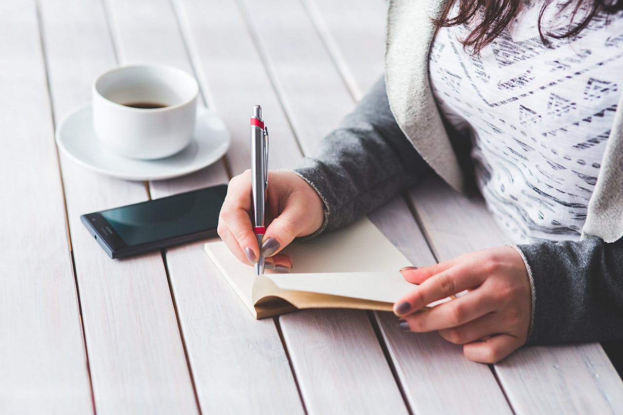 A woman writing in a note book on a desk