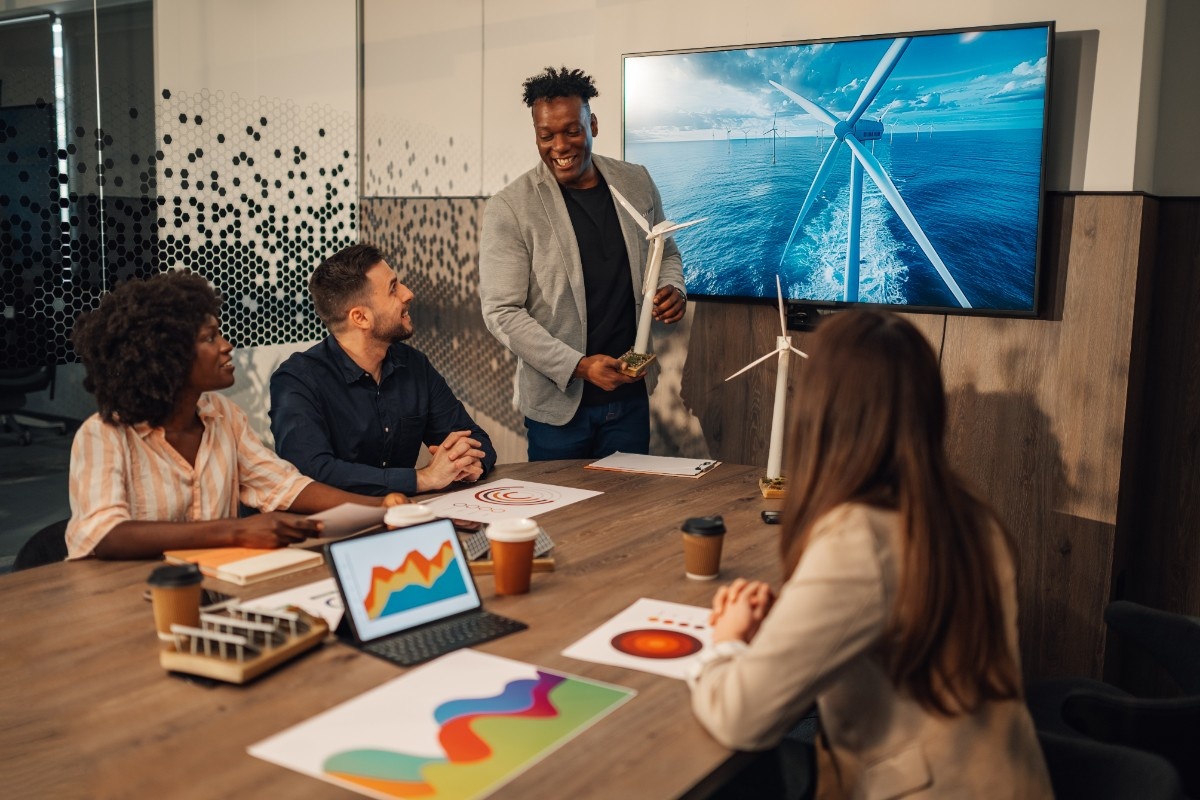 Diverse ecology expert presenting windmill model to investors at office