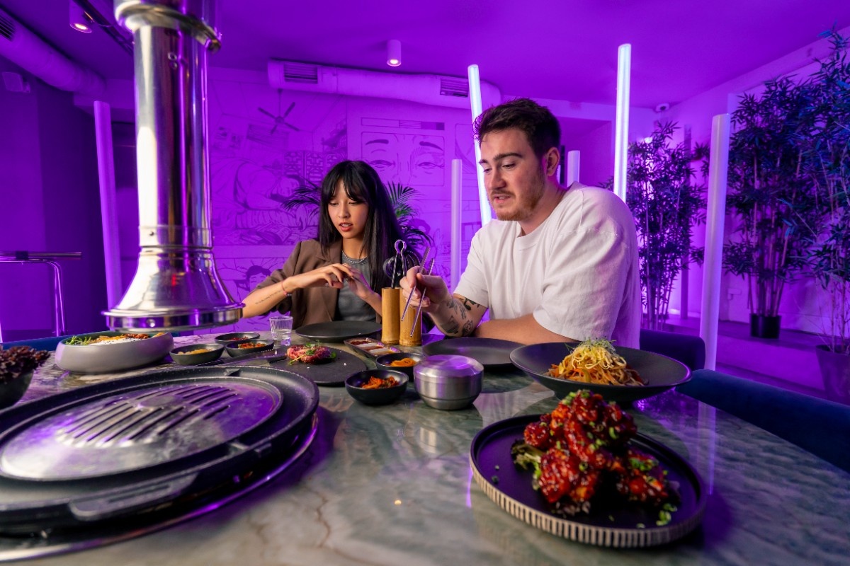 a couple in love in a korean restaurant with a grill and a hood above the table tastes dishes