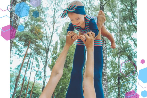 An image of legs with a baby lying face down on the feet, holding hands with the person below them and smiling down at the person An image of legs with a baby lying face down on the feet, holding hands with the person below them and smiling down at the person