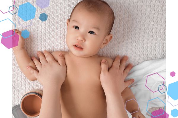 Image of a baby lying down, facing the camera. The image only shows from chest up where baby is enjoying skin-on-skin baby massage on their chest and shoulders. Image of a baby lying down, facing the camera. The image only shows from chest up where baby is enjoying skin-on-skin baby massage on their chest and shoulders.