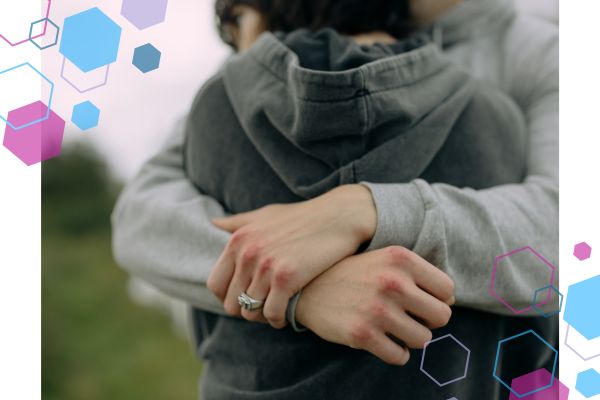 Image of someone's back, with someone else's hands clasped around them in a cuddle Image of someone's back, with someone else's hands clasped around them in a cuddle