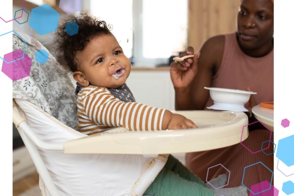 An image of a baby in a highchair with food around their mouth. A woman is in the background with a spoon. An image of a baby in a highchair with food around their mouth. A woman is in the background with a spoon.