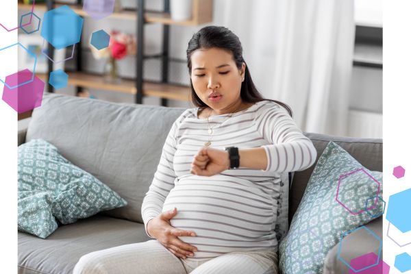 CubCare image of a hypermobile pregnant client of CubCare who is sitting on the edge of a sofa, with her mouth pouted as if out of breath, looking at her watch to check her heart rate - likely POTS due to hypermobility. CubCare image of a hypermobile pregnant client of CubCare who is sitting on the edge of a sofa, with her mouth pouted as if out of breath, looking at her watch to check her heart rate - likely POTS due to hypermobility.