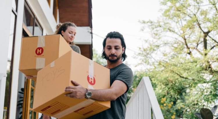 Couple carrying boxes on steps while moving out of house Couple carrying boxes on steps while moving out of house