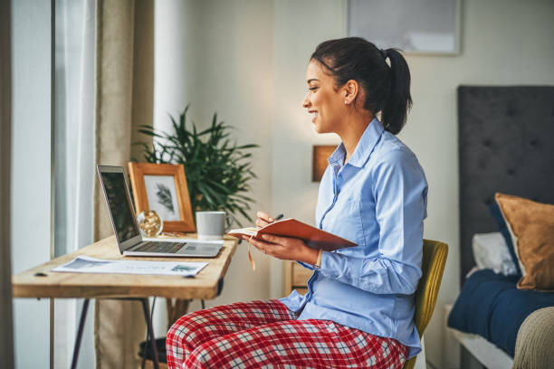 woman working at laptop wearing blouse on top and pajama pants