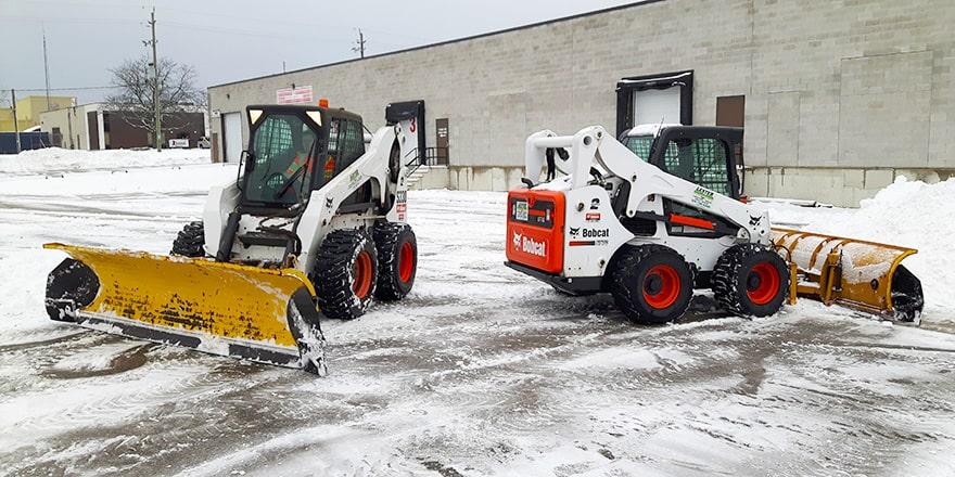 Various snow removal equipment including a snow plow, skid-steer loader, and salt spreader in a snowy environment Various snow removal equipment including a snow plow, skid-steer loader, and salt spreader in a snowy environment