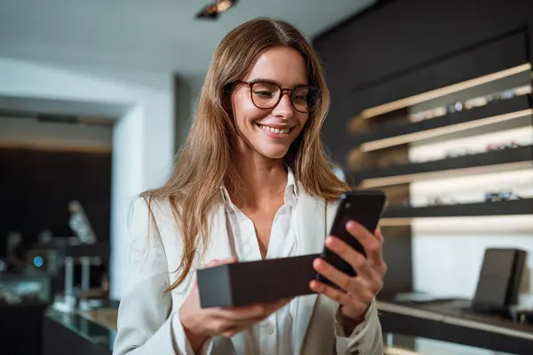 Happy optical patient leaving 5-star Google review on smartphone after luxury eyewear purchase in San Francisco