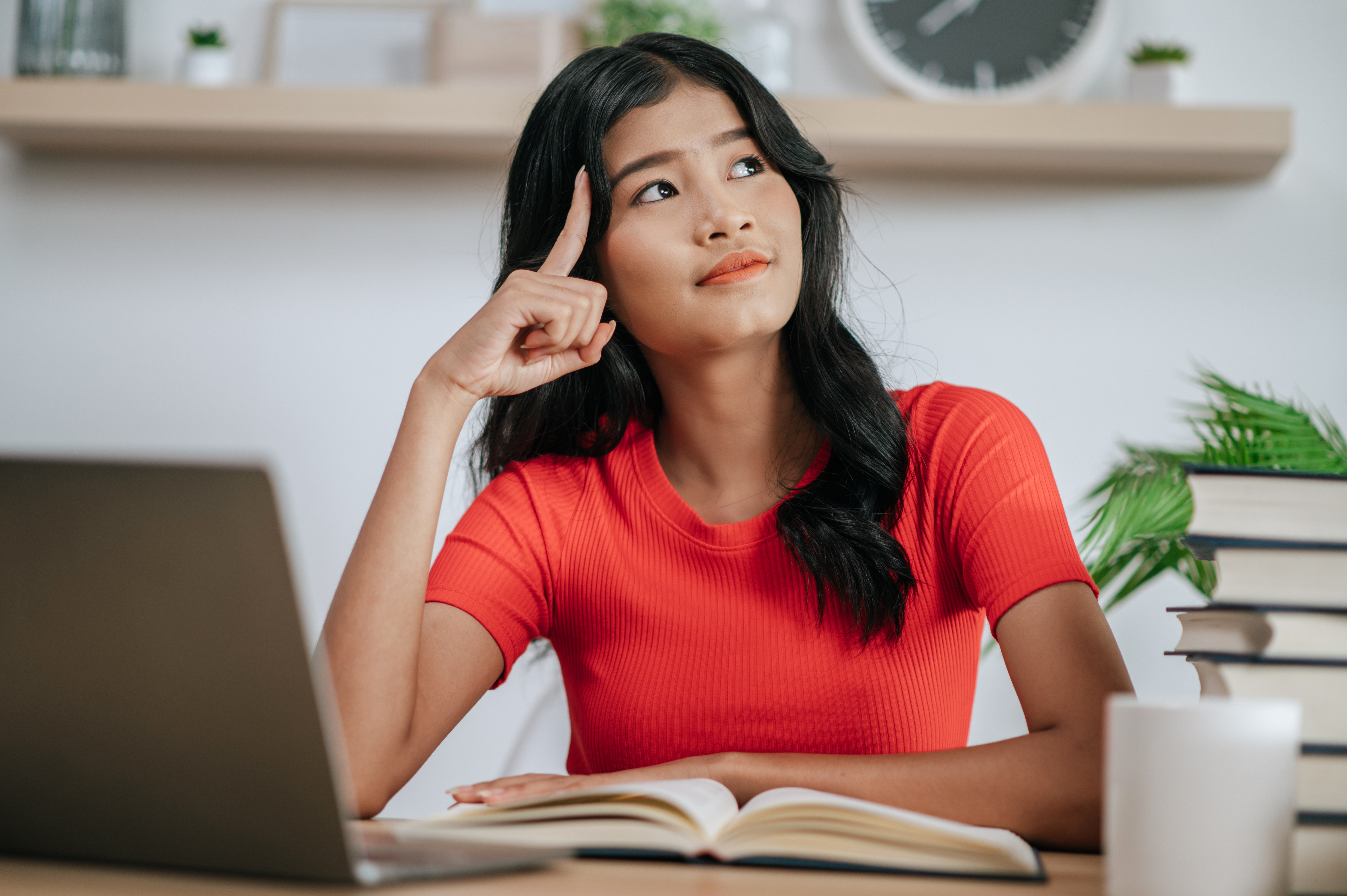 young woman working with laptop on desk and thinking 