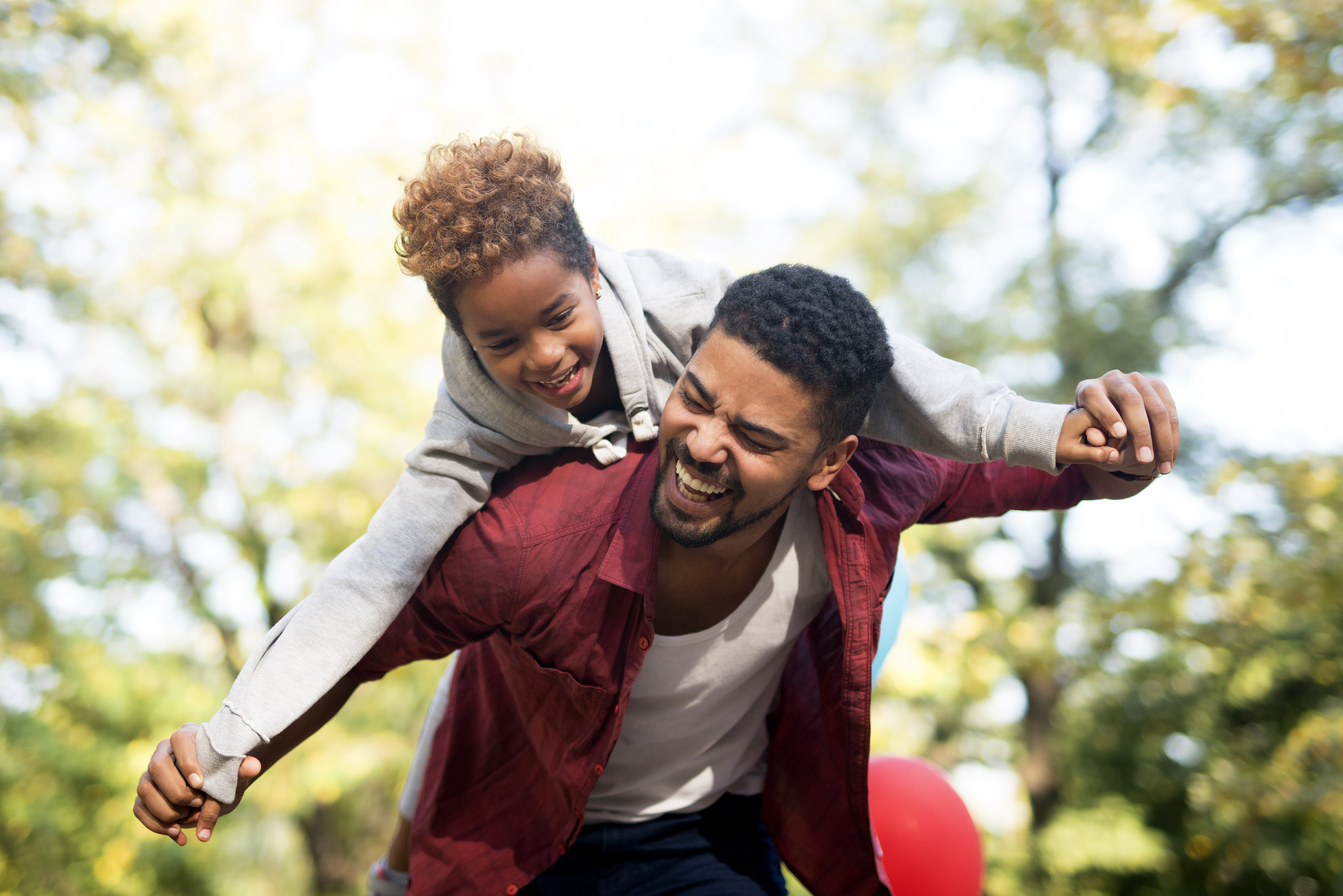  Father carrying daughter on his back with arms spread