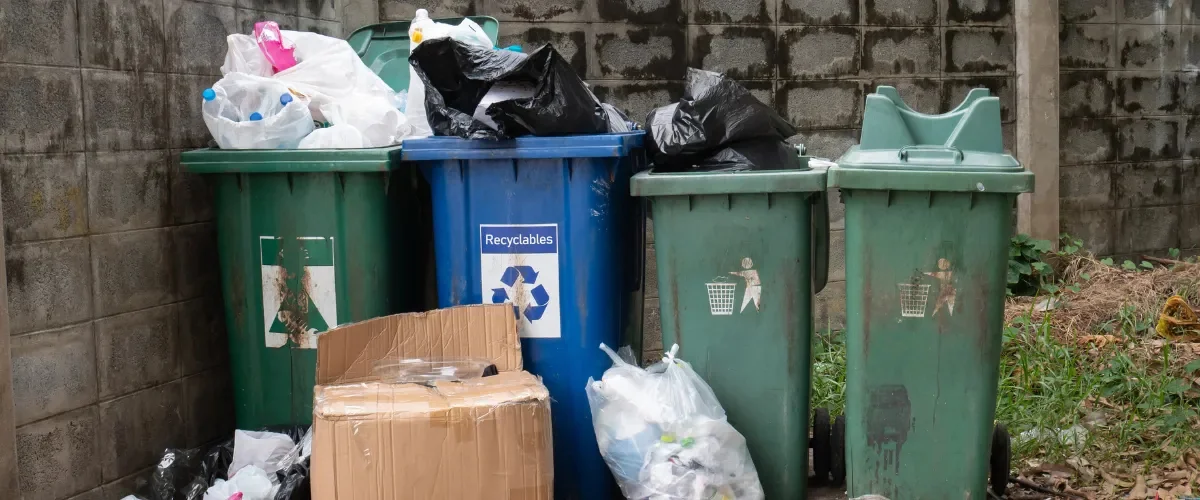 Overflowing trash and recycling bins with garbage bags and waste buildup. Overflowing trash and recycling bins with garbage bags and waste buildup.