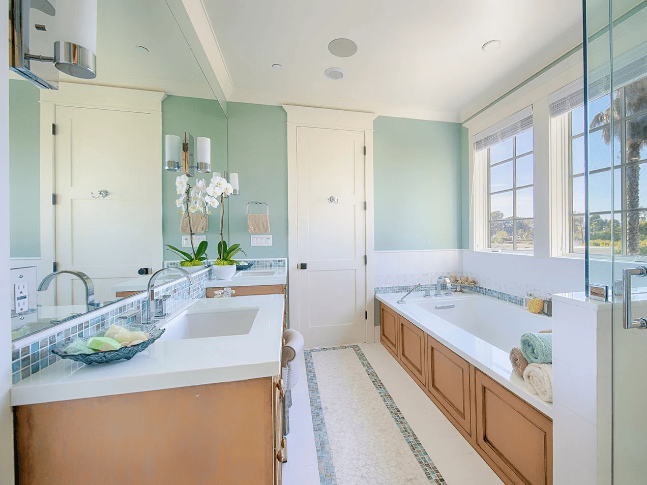 a beautifully remodeled bathroom featuring a dual vanity with modern sinks, a built-in bathtub, and a glass-enclosed shower.
