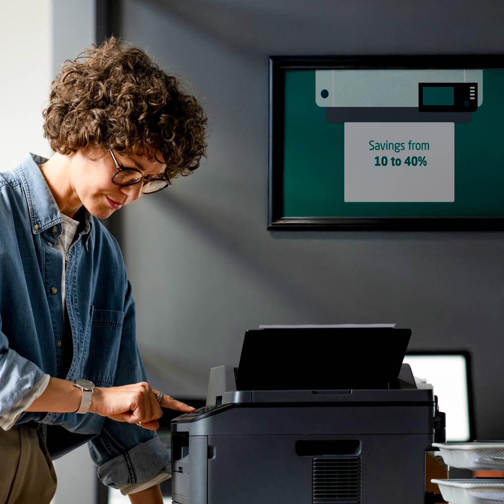 Woman in her 30's next to a printer pushing a button