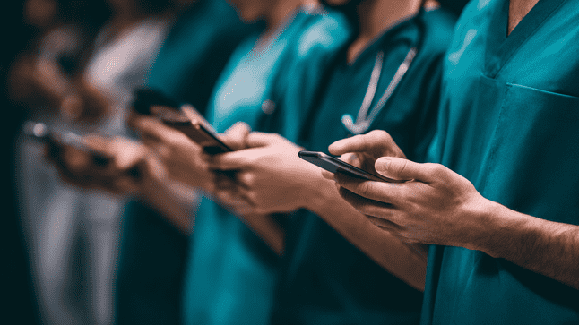 Healthcare professionals in scrubs using smartphones simultaneously, illustrating cross-platform communication, SMS outreach, and real-time engagement in modern healthcare recruiting.