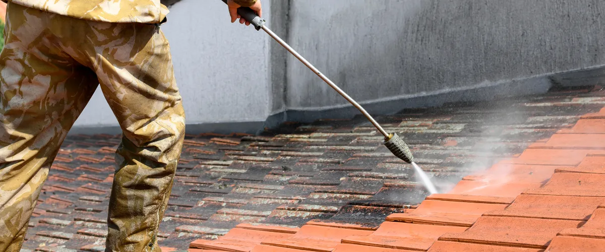 Professional roof cleaning using high-pressure washing to remove dirt and moss.