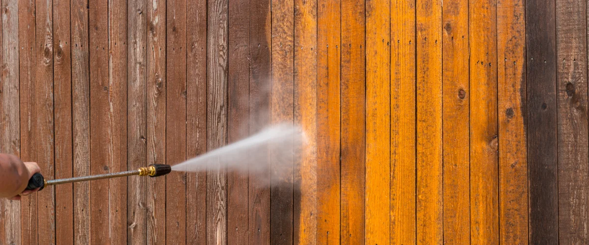 Pressure washing a wooden fence to restore natural color