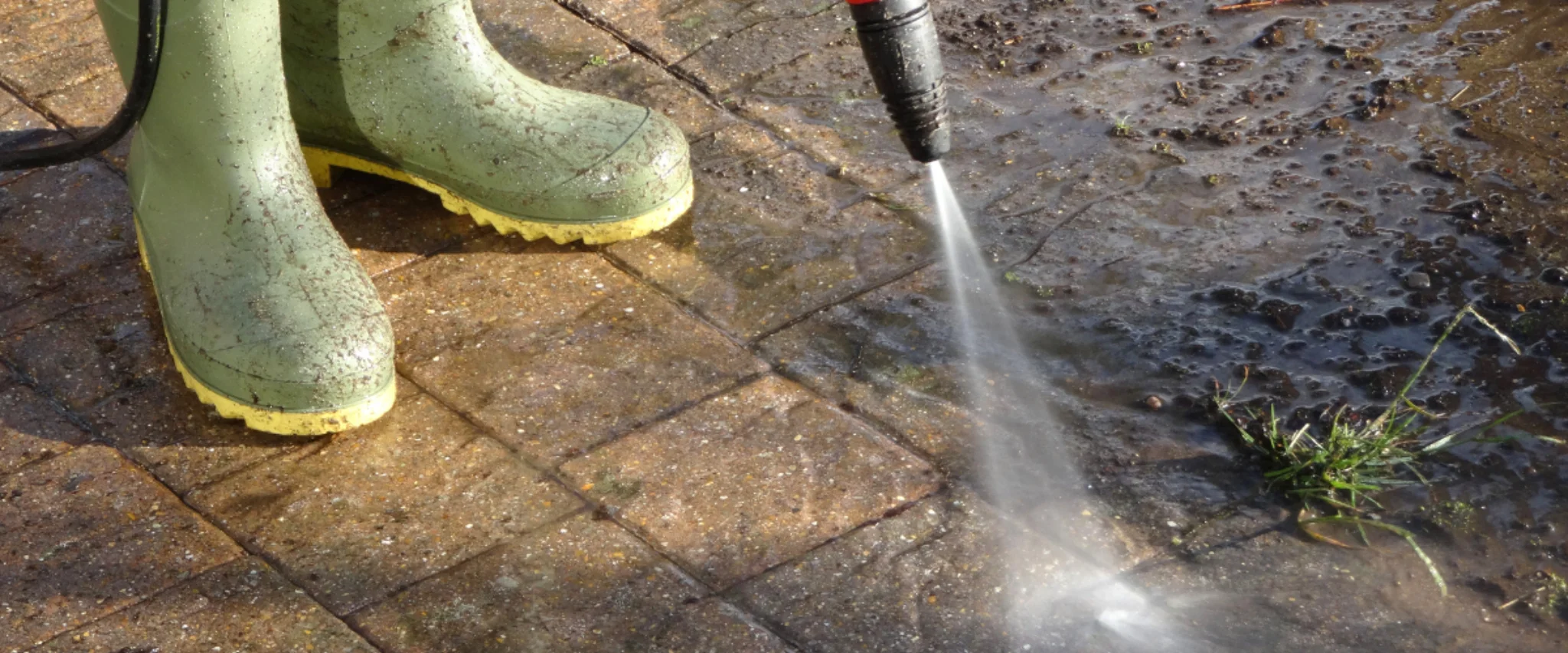 Pressure washing patio pavers with water spray near rubber boots Pressure washing patio pavers with water spray near rubber boots