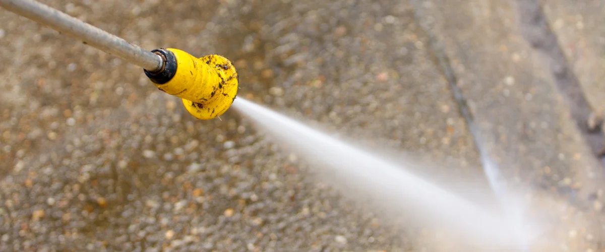 Pressure washer nozzle spraying water onto concrete surface Pressure washer nozzle spraying water onto concrete surface