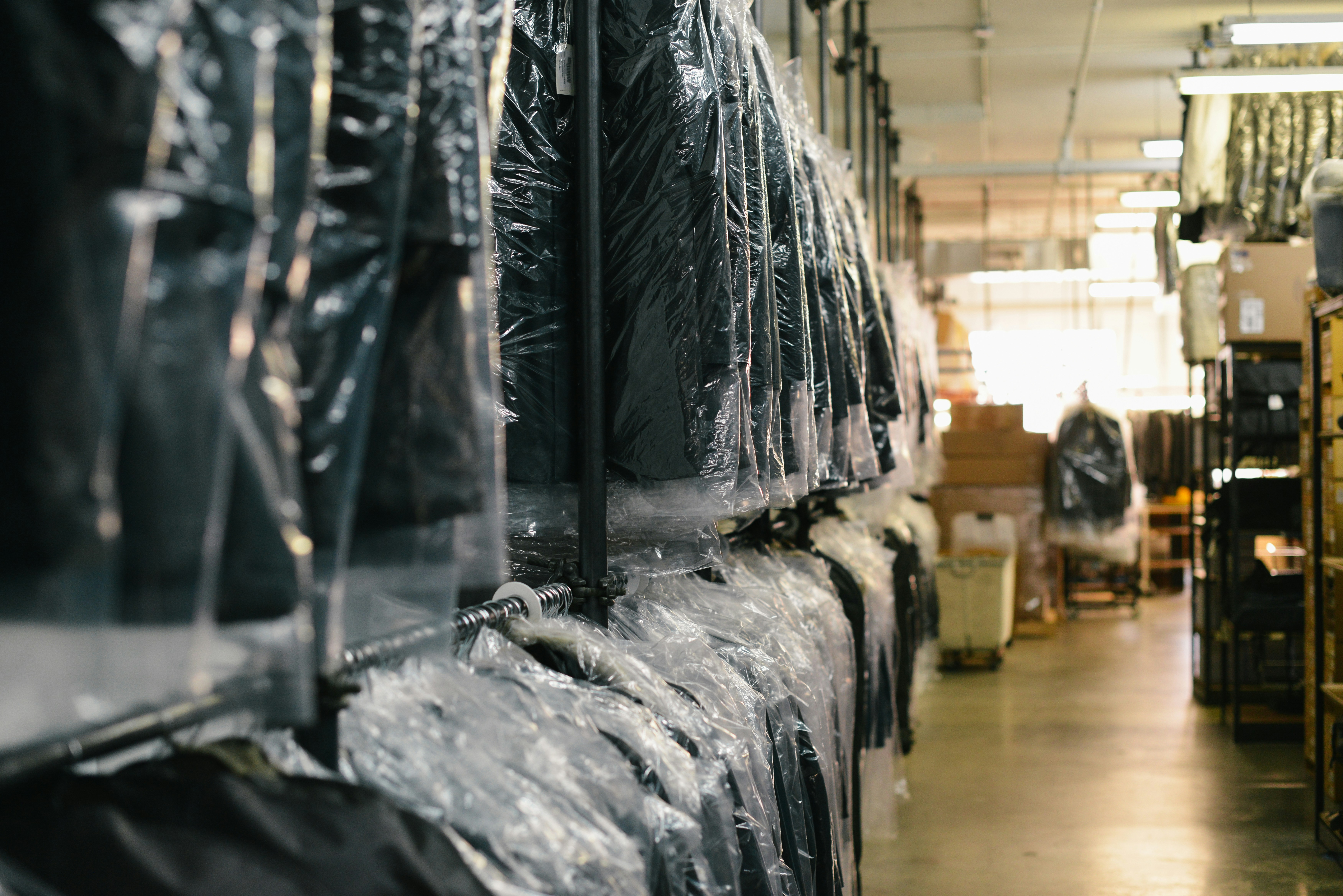 a drycleaner full of suits that have been cleaned and a garment bag over top a drycleaner full of suits that have been cleaned and a garment bag over top