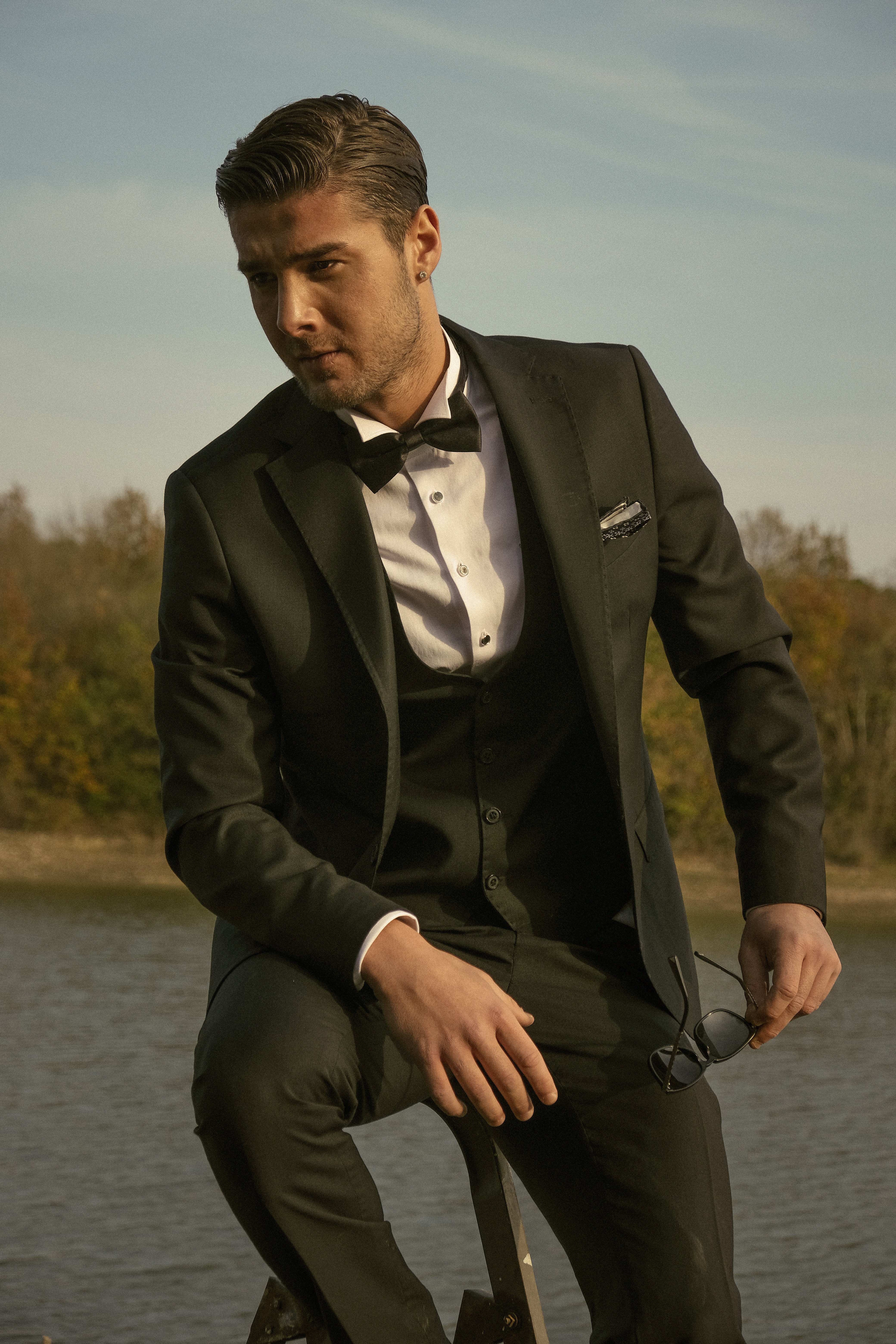 A man in a black suit with a black vest, white dress shirt, black bow tie and white pocket square A man in a black suit with a black vest, white dress shirt, black bow tie and white pocket square