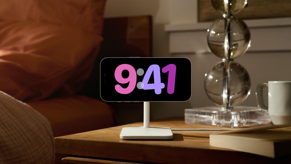 An iPhone being used as a clock beside a bed, displaying the time 9:41.