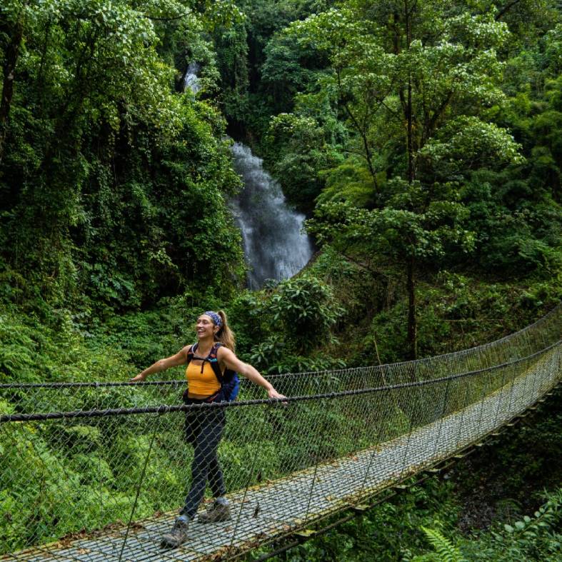Person walking on suspension bridge through Nepalese jungle