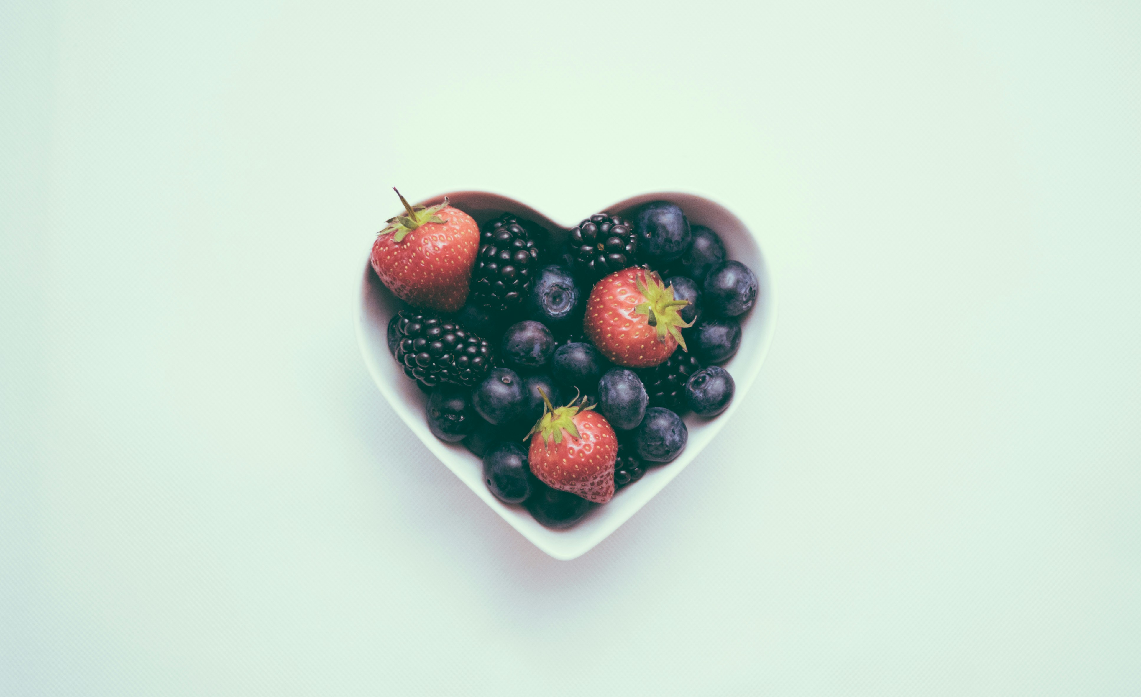 Heart-shaped bowl full of red berries Heart-shaped bowl full of red berries