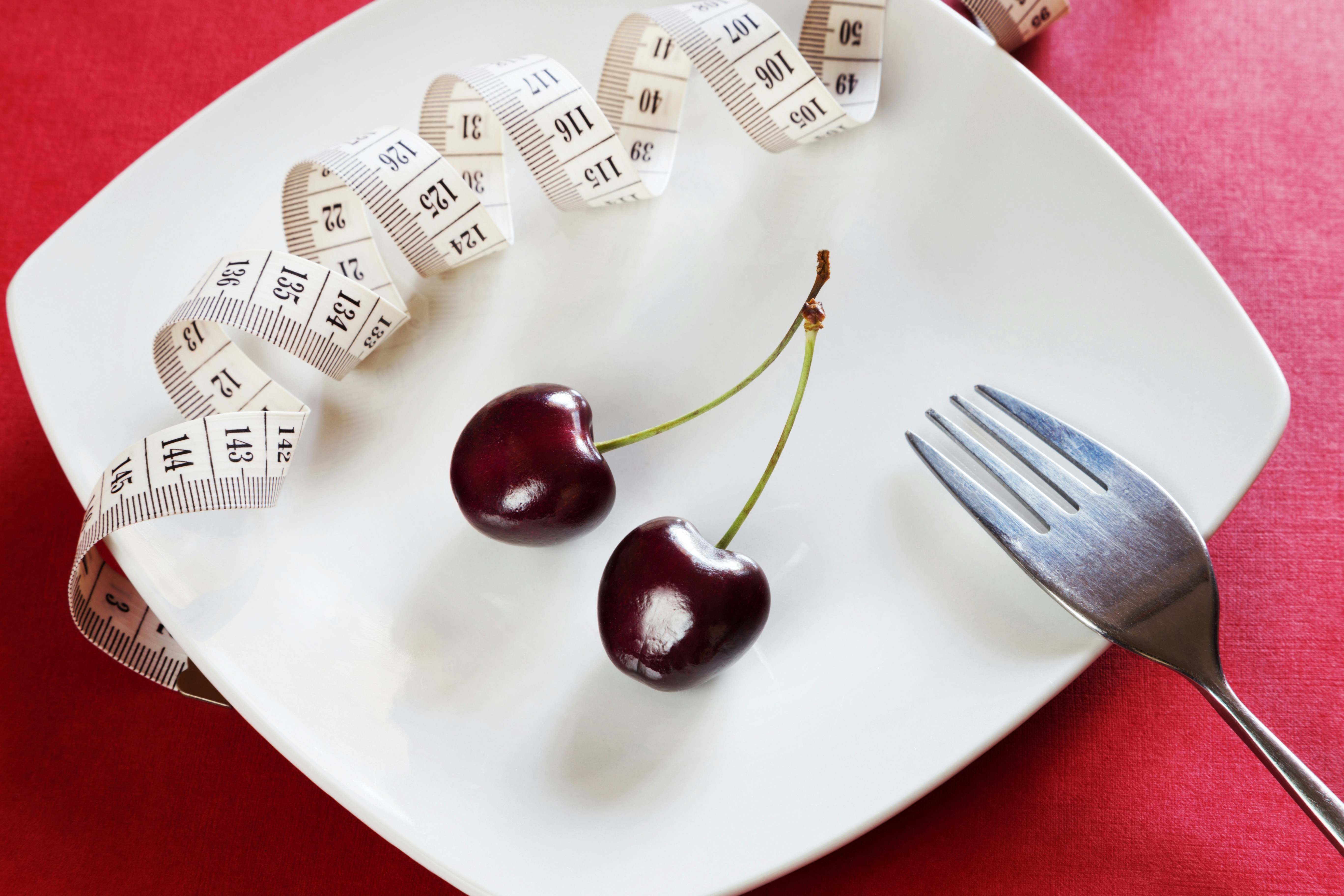 black cherries on a white plate with a measuring tape black cherries on a white plate with a measuring tape