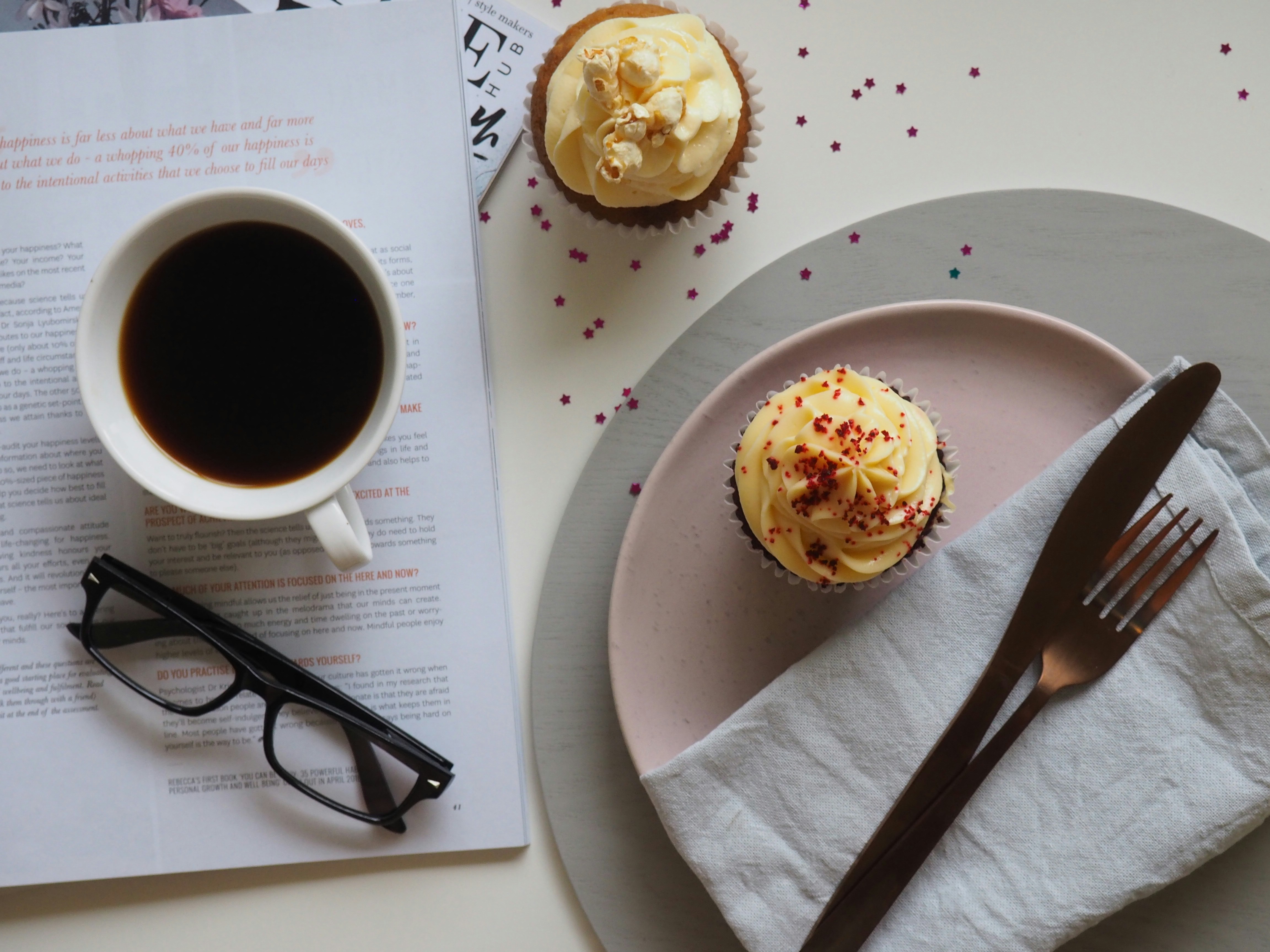 laptop with a cup of coffee next to it and two cupcakes laptop with a cup of coffee next to it and two cupcakes