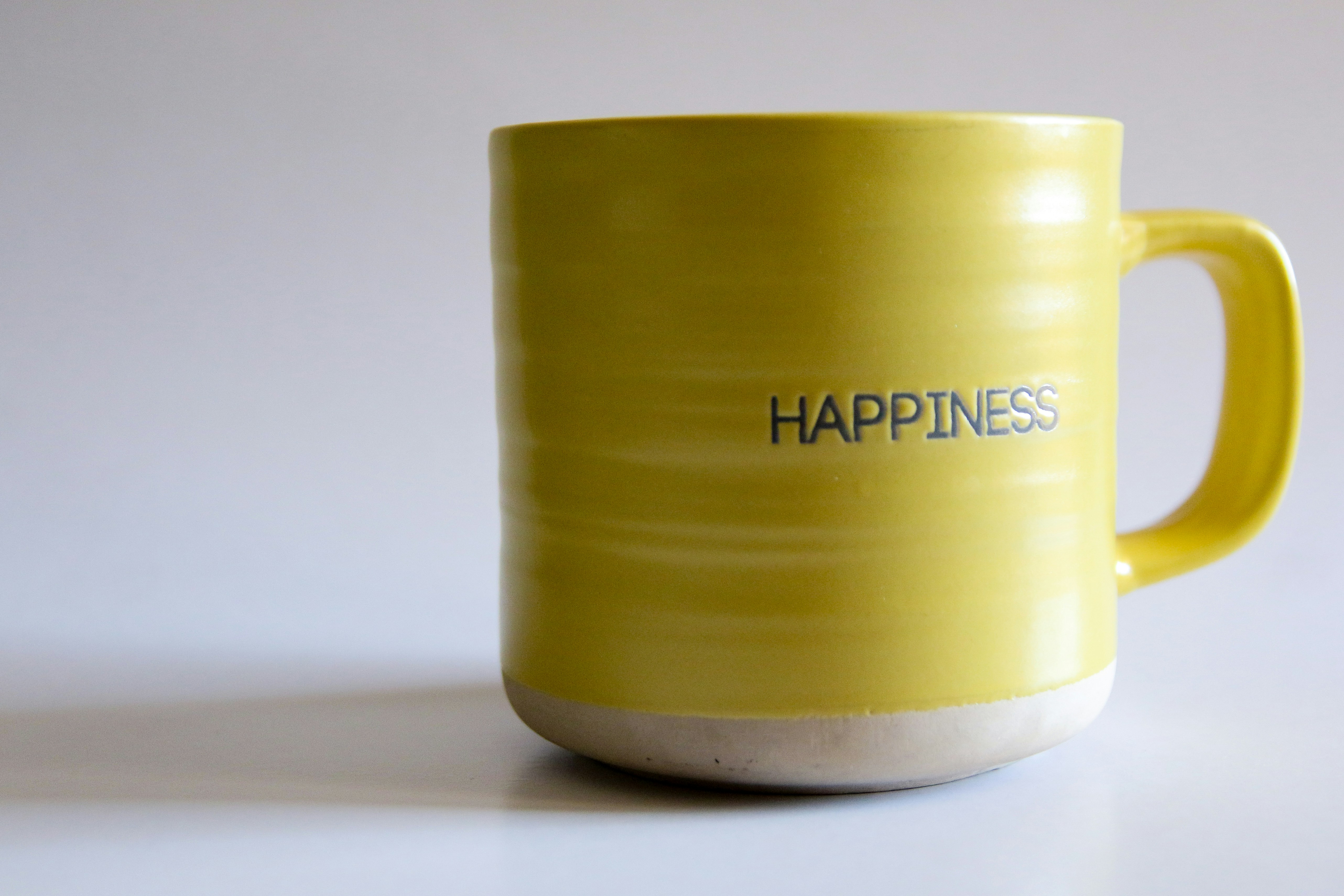 Yellow cup with Happiness written on it Yellow cup with Happiness written on it