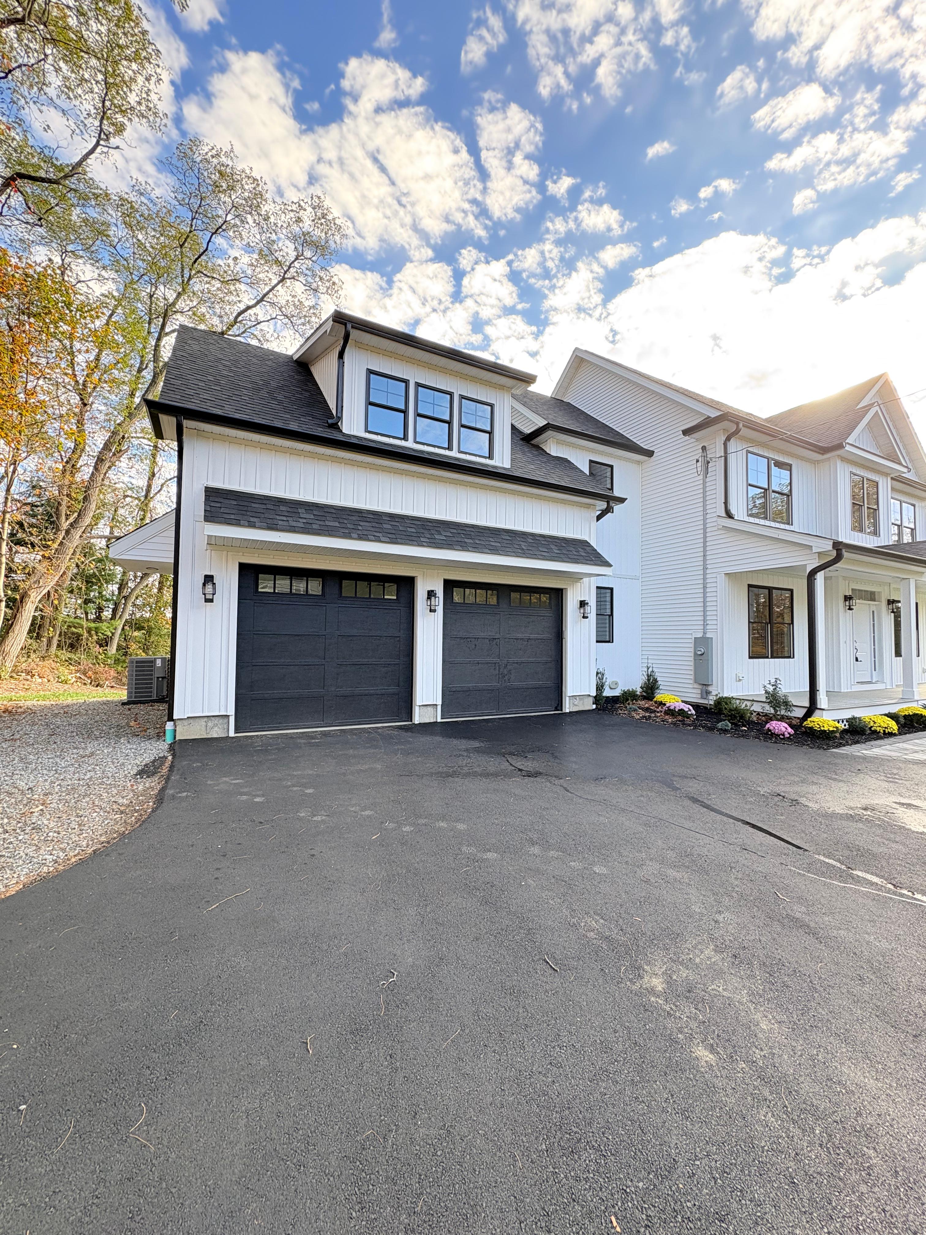 Modern black garage doors installed on white home in Easton CT