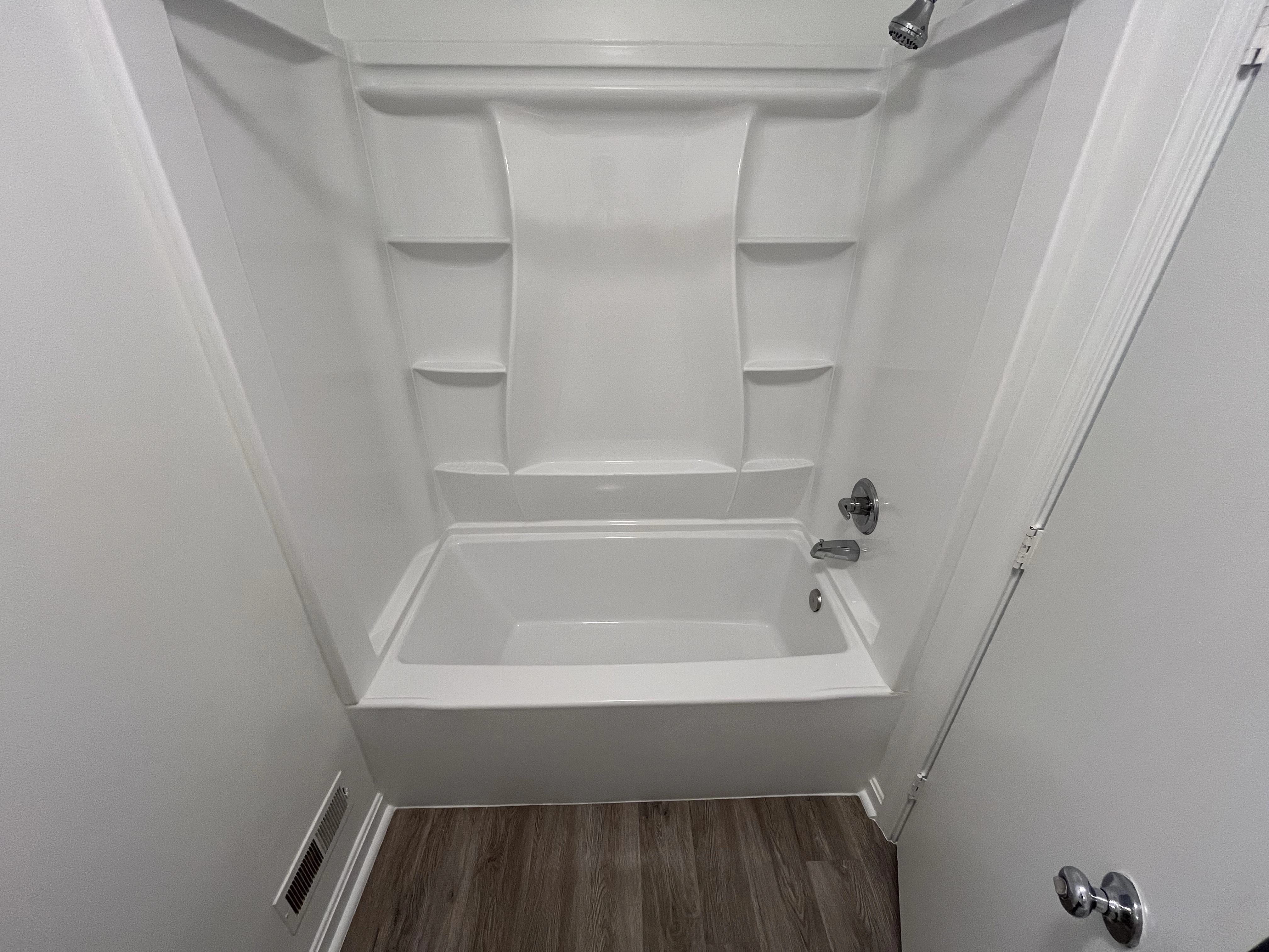 A spacious bathroom showcasing a tub and shower combination, accented by contemporary decor and lighting.